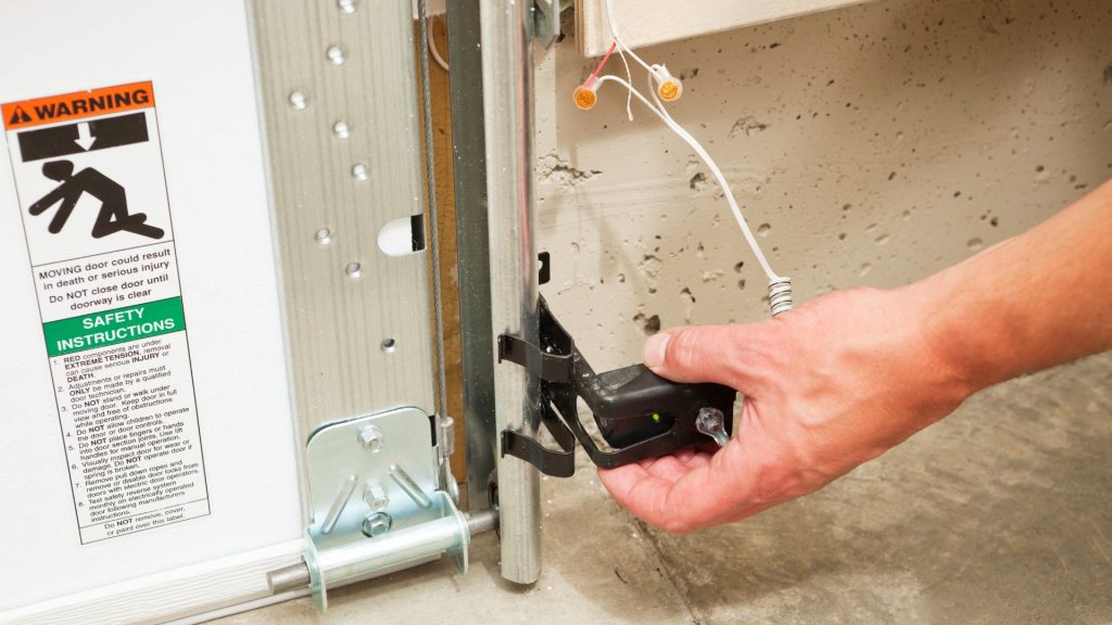 A homeowner troubleshooting a garage door safety sensor