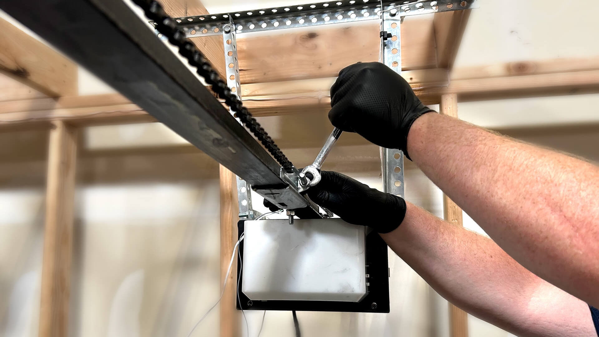 A technician tightening the hardware as part of a quarterly garage door opener maintenance