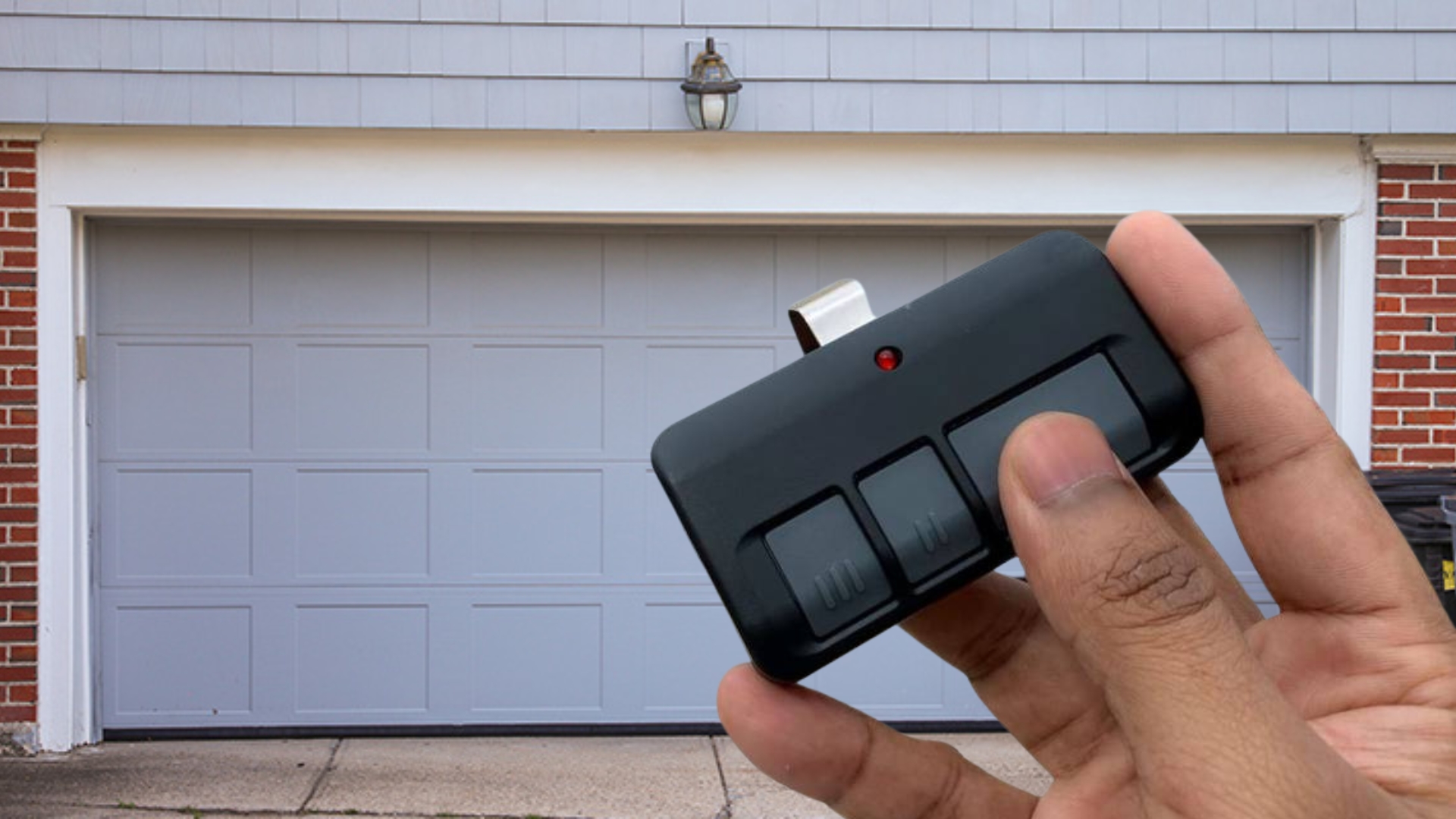 A man holding the remote control in front of their residential garage door