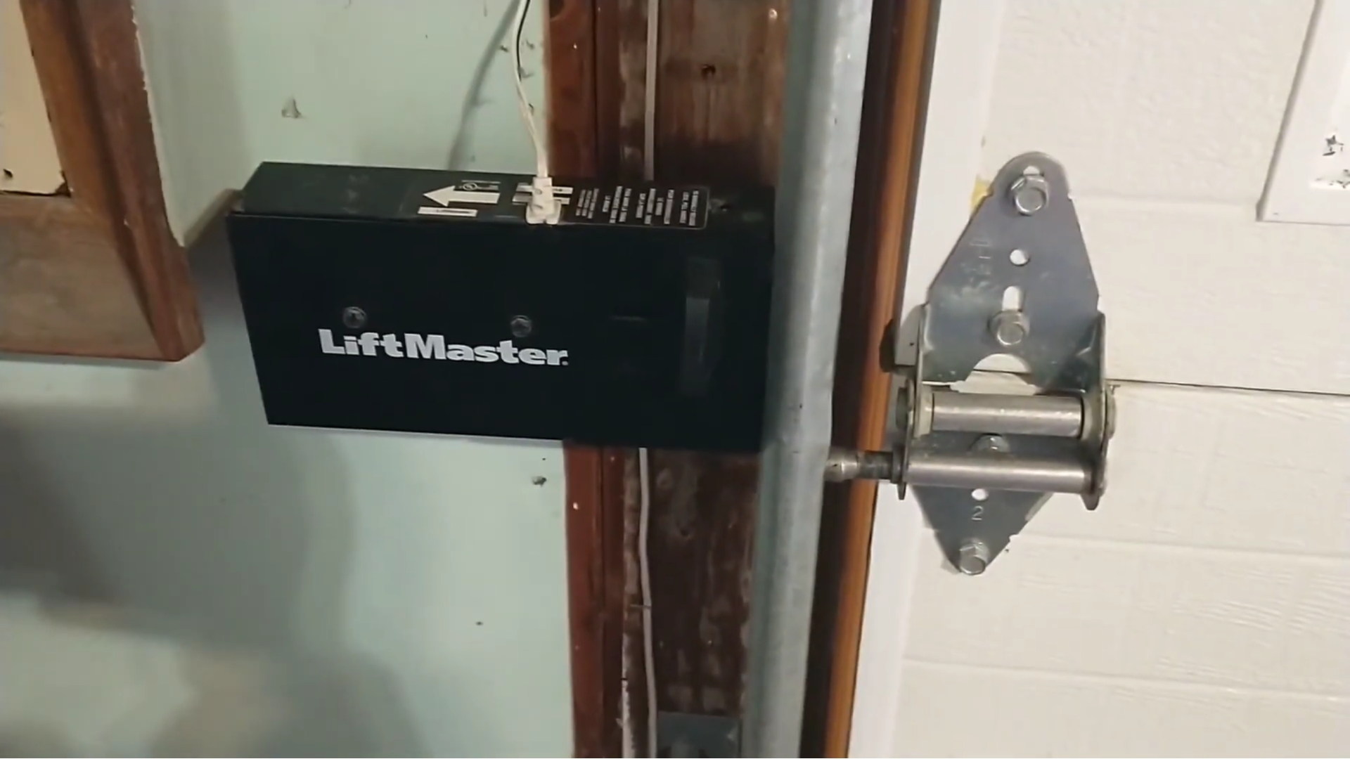 A LiftMaster garage door latch installed on the side of the frame