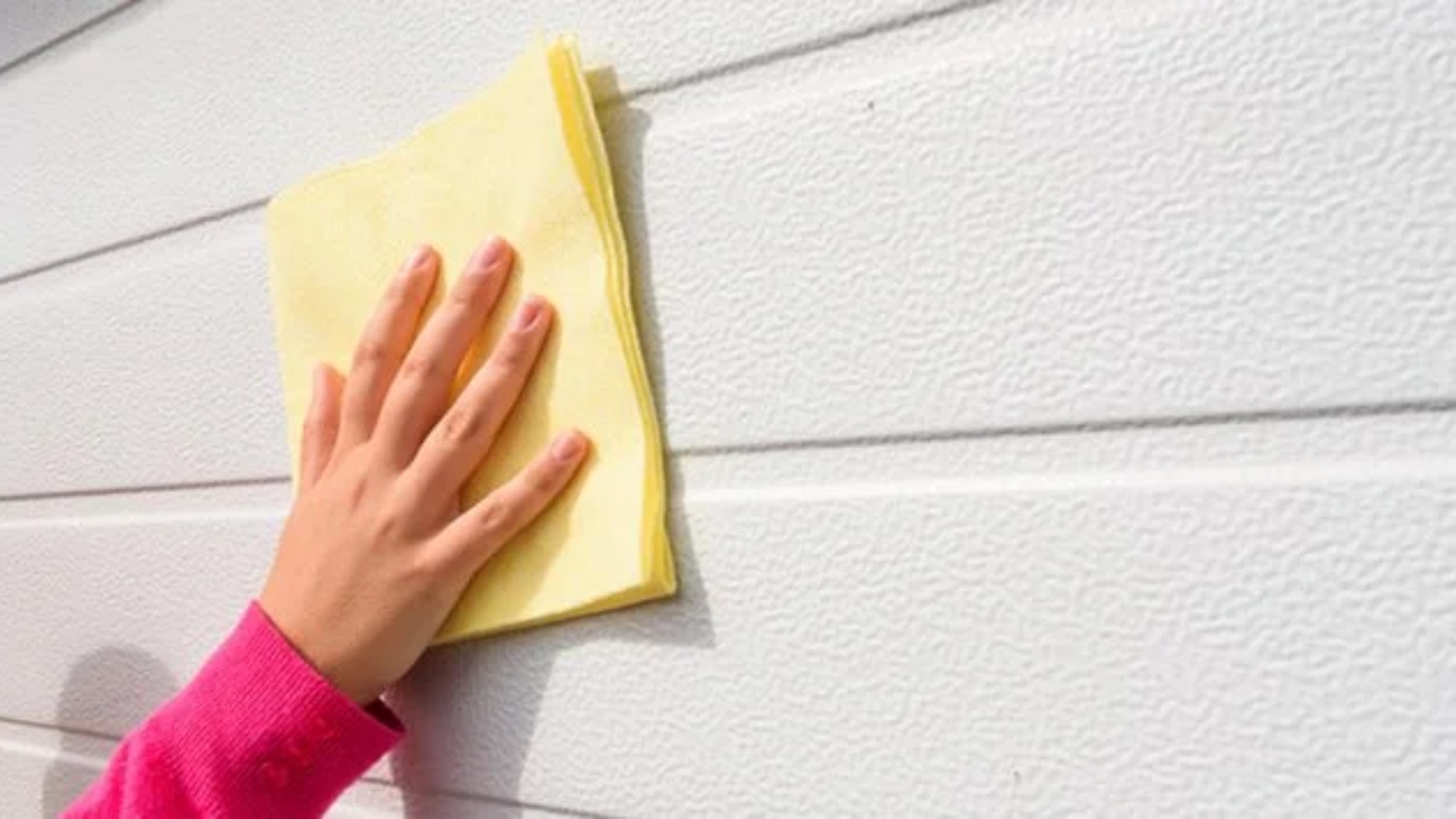 A person cleaning the garage door with a cloth to prevent rusting