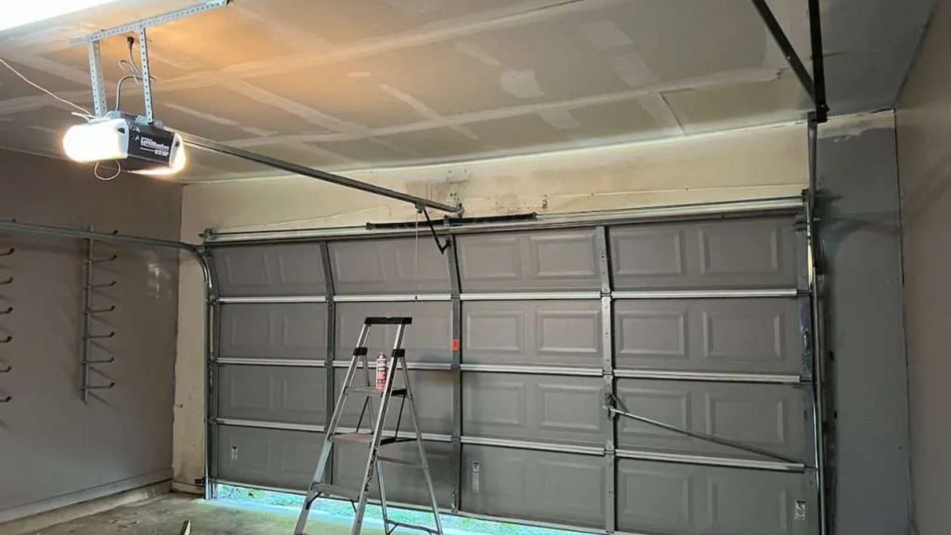 A closed residential garage door with an opener that lights up