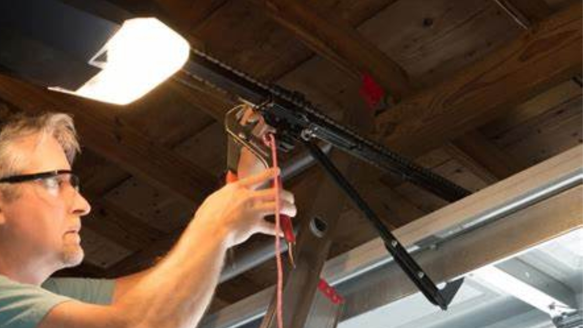 A man adjusting the garage door opener bracket for stability