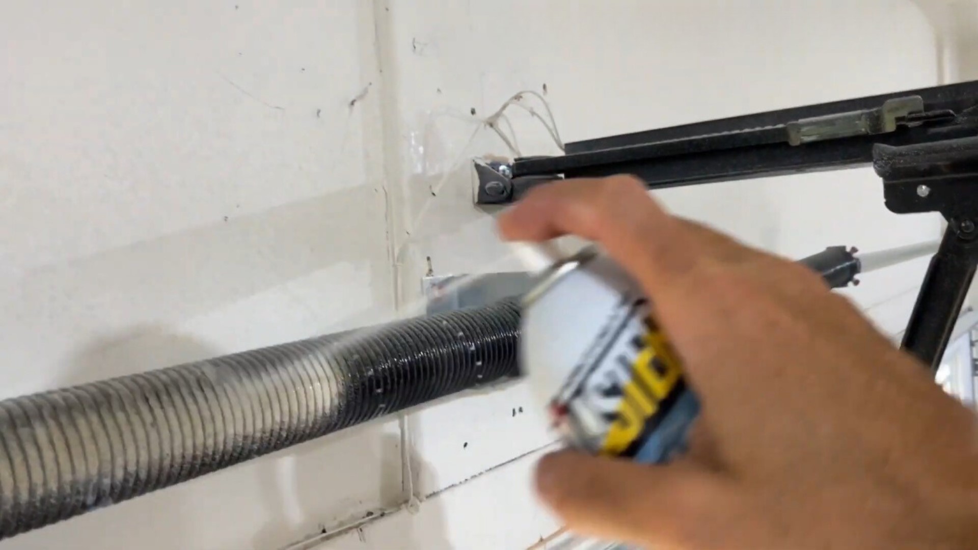 Using spray lubricant on springs to prevent squeaky garage doors.