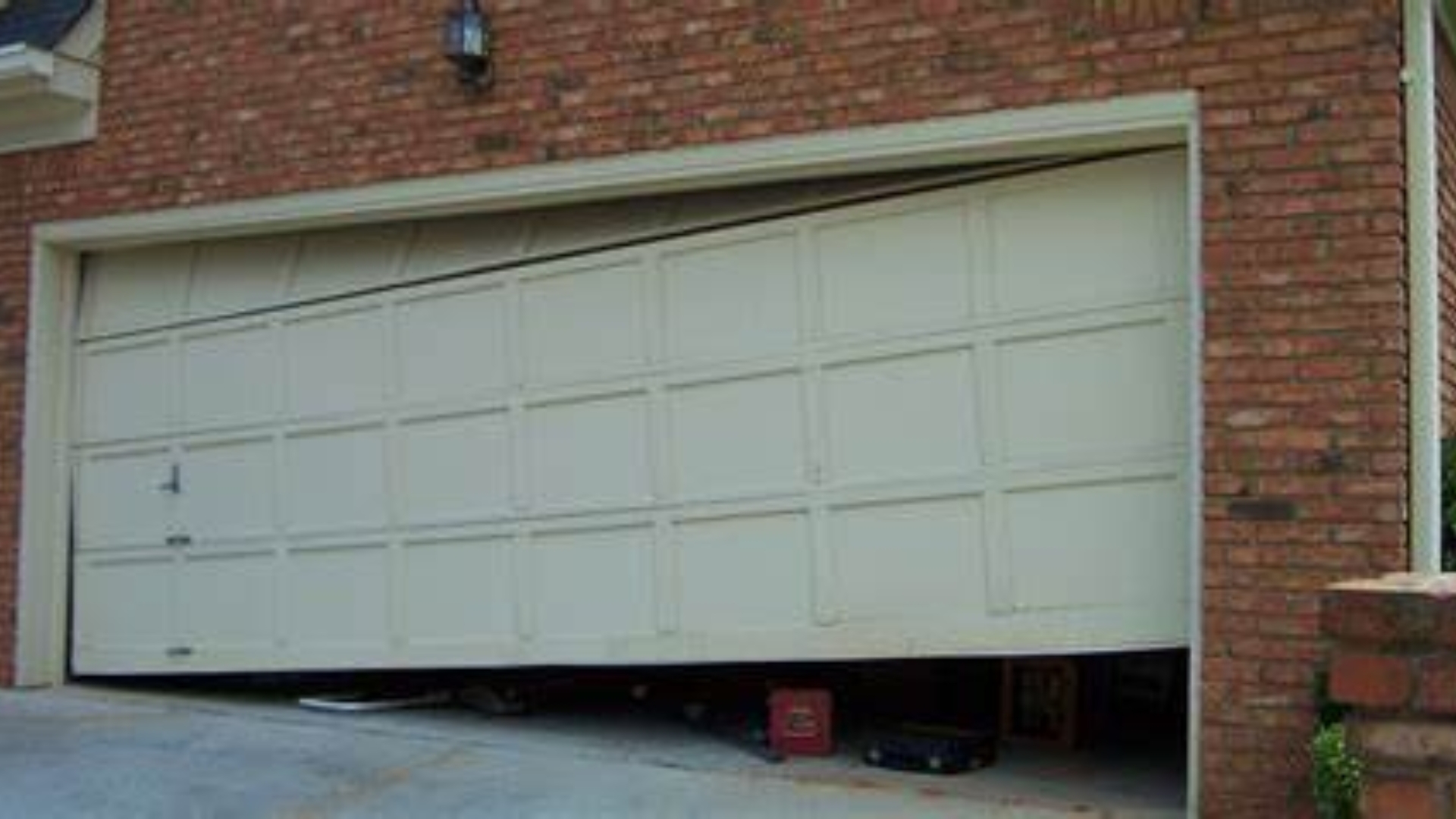 A garage door off track due to bent panels—requires immediate repair.