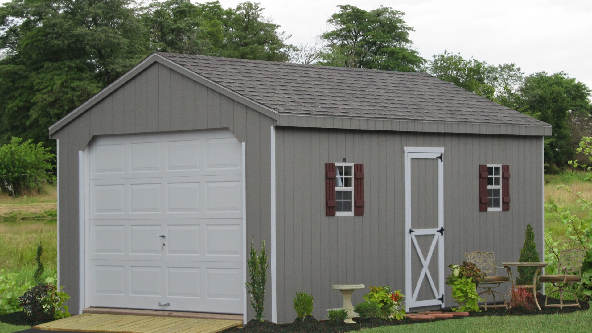 A detached garage with a small garage door and side barn-style door.