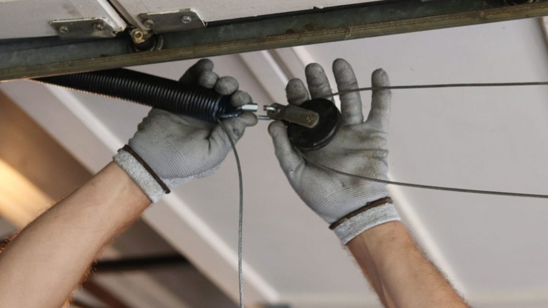 Tightening a garage door spring during a routine maintenance visit