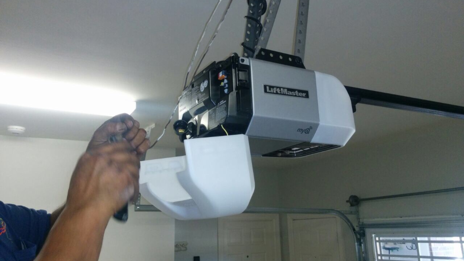 A technician checking garage door opener wiring to resolve light flickering issues